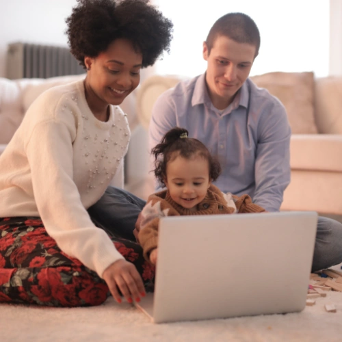 Parents and child smiling while looking at a tablet together, enjoying internet services in the kitchen.